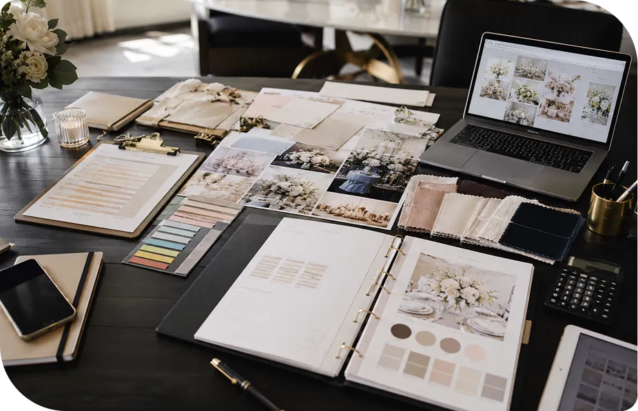 Wedding planning workbook, swatches and laptop on a desk